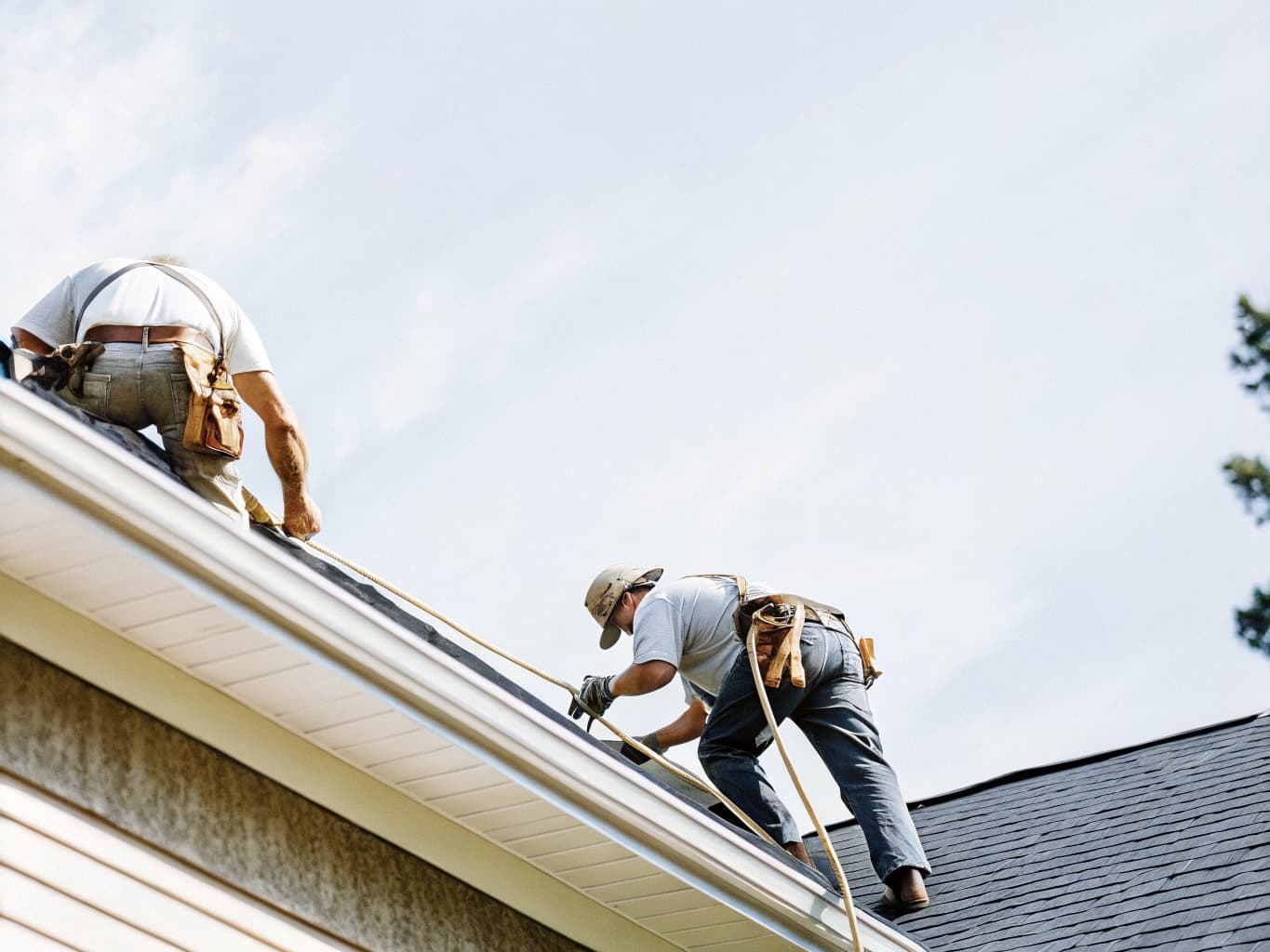 Roofing contractors installing shingles on a Cape Cod home
